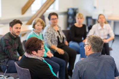 Gruppenbesprechung in der Alterspsychiatrie Die Teilnehmer der Besprechung hören der Patientin aufmerksam zu