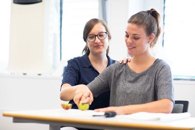 Die Patientin schneidet mit Unterstützung einen Apfel