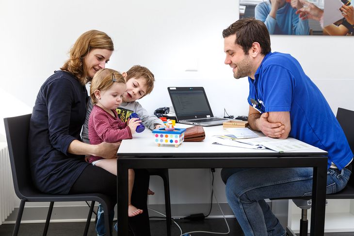 Ein Hausarzt bei der Sprechstunde mit einer jungen Familie