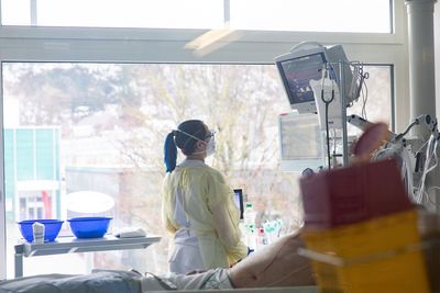 Eine Pflegerin kontrolliert das Gerät neben einem Patienten