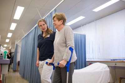 Physiotherapie Die Physiotherapeutin begleitet eine Patientin in Krücken