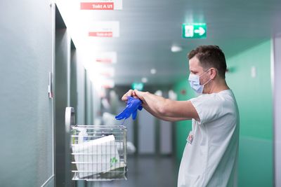 Hygiene Eine Pfleger zieht Handschuhe an