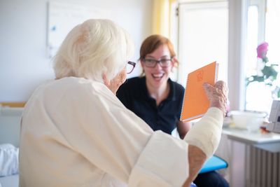 Sozialberatung Eine Mitarbeiterin spricht mit einer älteren Patientin