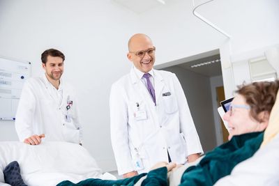 Arztvisite Zwei Ärzte sprechen mit Patientin am Bett