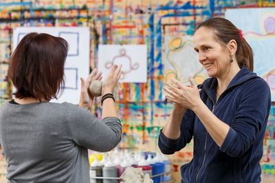 Kunsttherapie in den Psychiatrischen Diensten Zwei Frauen formen eine Knetmasse, im Hintergrund sind Bilder zu sehen