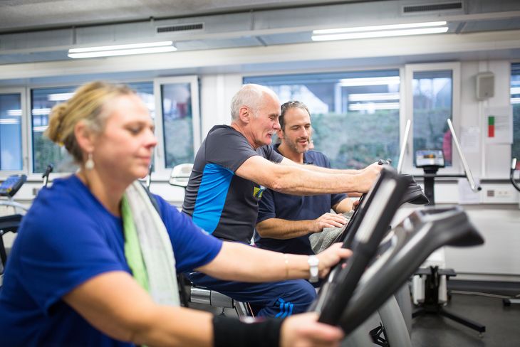Der Physiotherapeut hilft einem Mann bei einem Fitnessgerät